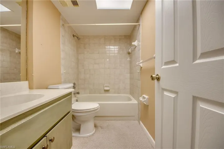 Full bathroom featuring vanity, tiled shower / bath combo, and toilet