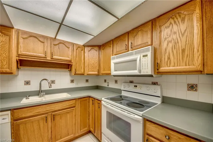 Kitchen featuring backsplash, sink, and white appliances