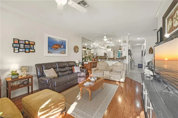 Living area with ornamental molding, a ceiling fan, and wood finished floors
