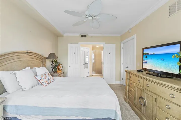 Bedroom with crown molding, light colored carpet, and ceiling fan