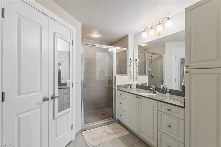 Full bathroom with a stall shower, vanity, light tile patterned flooring, and a textured ceiling