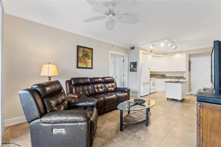 Living area with ornamental molding, track lighting, light tile patterned floors, and a ceiling fan