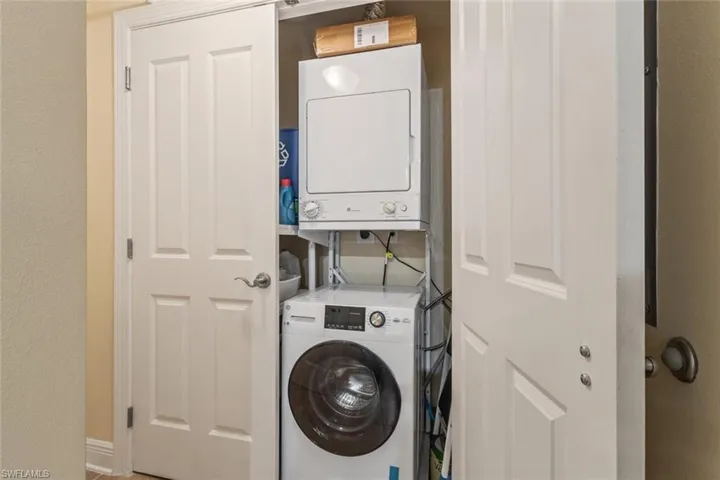 Laundry area featuring stacked washing machine and dryer and a textured wall