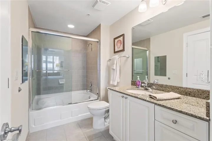 Bathroom with vanity, enclosed tub / shower combo, light tile patterned floors, and recessed lighting