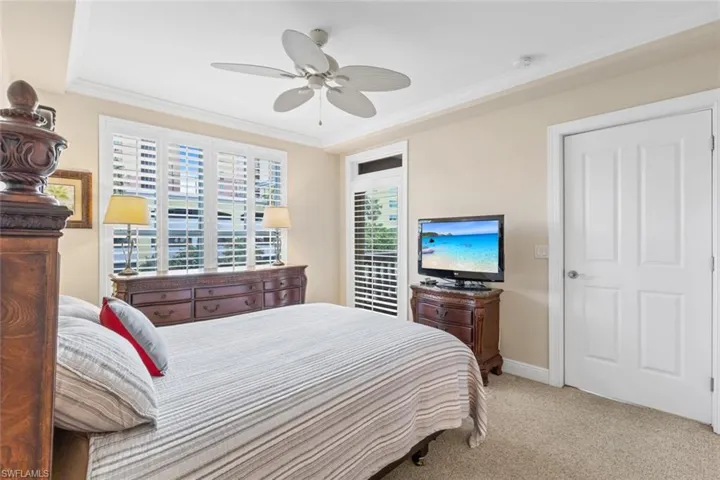Bedroom featuring light carpet, ornamental molding, and ceiling fan