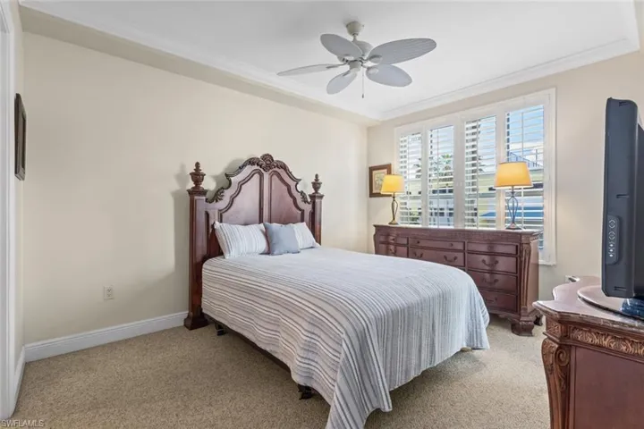 Bedroom featuring ornamental molding, light colored carpet, and ceiling fan
