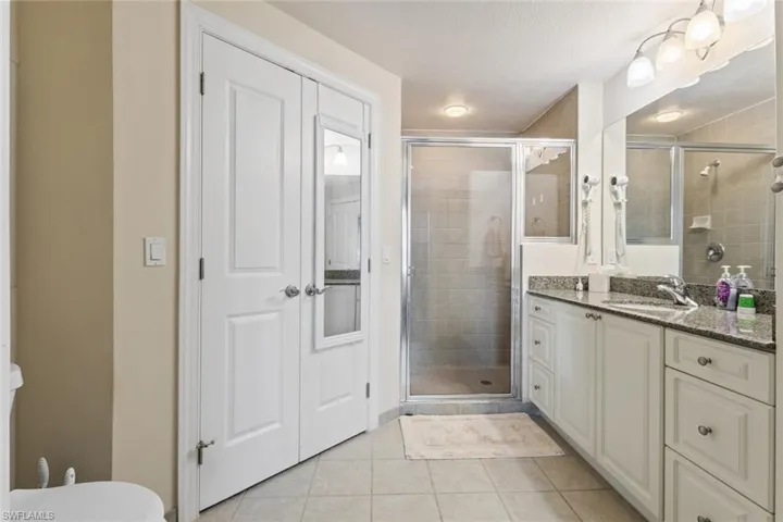 Bathroom with light tile patterned floors, a stall shower, and vanity