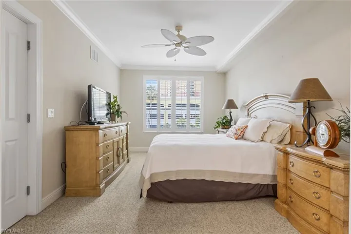 Bedroom featuring light carpet, crown molding, and a ceiling fan