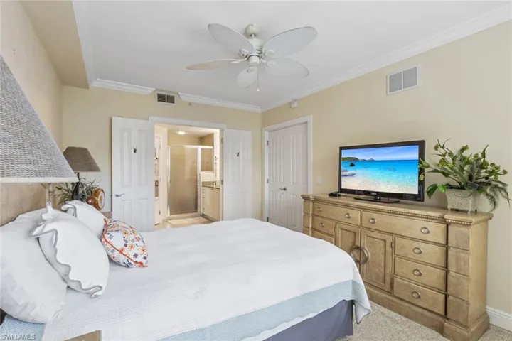Bedroom featuring ornamental molding, light carpet, ceiling fan, ensuite bathroom, and a closet