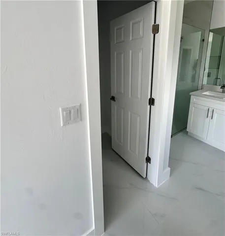 Hallway featuring light marble finish floors and a sink