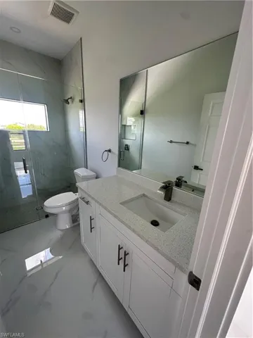 Bathroom featuring a marble finish shower, vanity, and marble finish floors