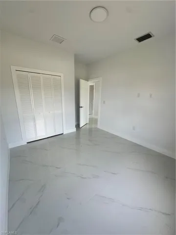 Unfurnished bedroom with marble look tile flooring and a closet