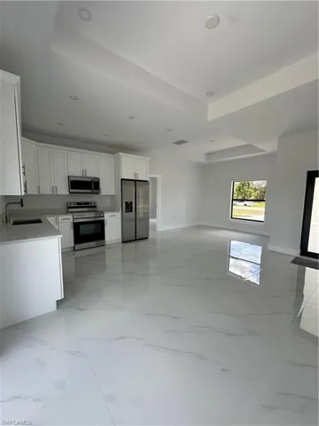 Kitchen with stove, fridge, open floor plan, and light marble finish flooring