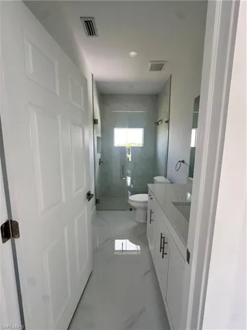 Full bath with marble look tile flooring, a marble finish shower, vanity, and recessed lighting