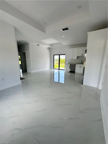 Unfurnished living room with recessed lighting, a raised ceiling, and light marble finish floors