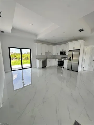Kitchen with fridge, range, dishwasher, a raised ceiling, and white cabinets
