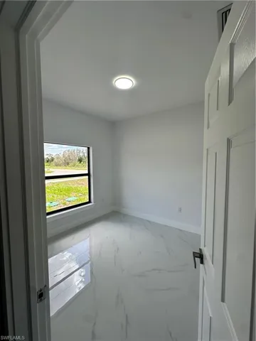 Unfurnished room featuring marble finish flooring and baseboards
