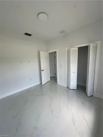 Unfurnished bedroom featuring light marble finish floors and a closet