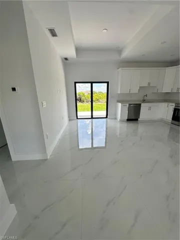 Unfurnished living room featuring a raised ceiling and light marble finish flooring