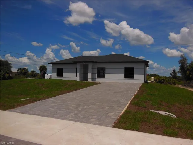 Contemporary home featuring driveway, stucco siding, and a front yard