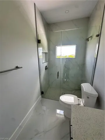 Full bathroom featuring a marble finish shower, marble look tile flooring, and vanity