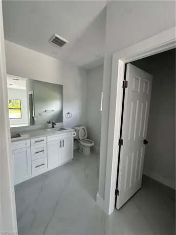 Bathroom with double vanity and marble finish flooring