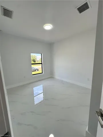 Unfurnished room featuring light marble finish floors and baseboards