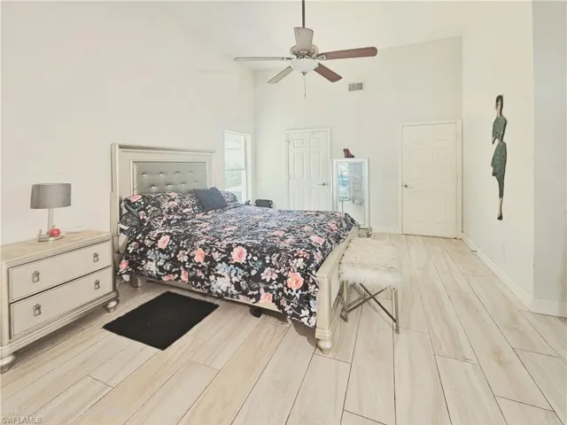Bedroom featuring light wood-style floors, high vaulted ceiling, and ceiling fan