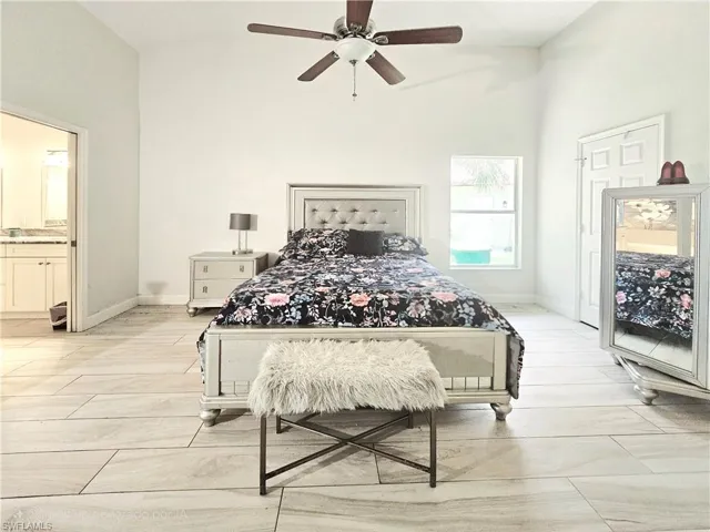 Bedroom with a ceiling fan, a towering ceiling, and ensuite bath