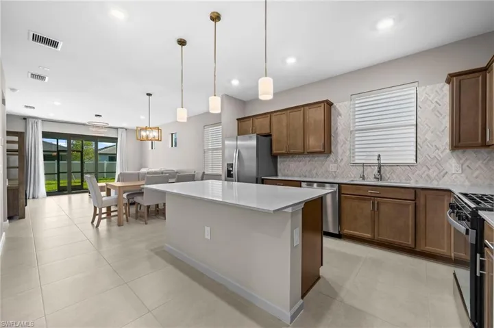 Kitchen featuring a center island, decorative light fixtures, brown cabinetry, decorative backsplash, and recessed lighting