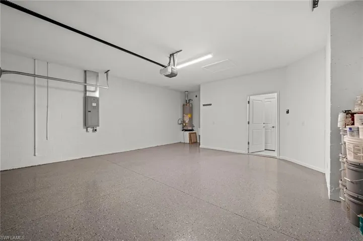 Garage featuring concrete block wall, electric panel, and water heater