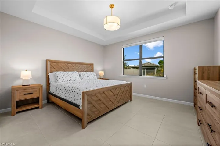 Bedroom featuring a tray ceiling and light tile patterned floors