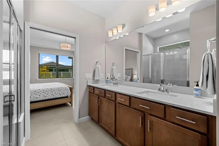 Bathroom with ensuite bath, double vanity, a shower stall, and light tile patterned floors