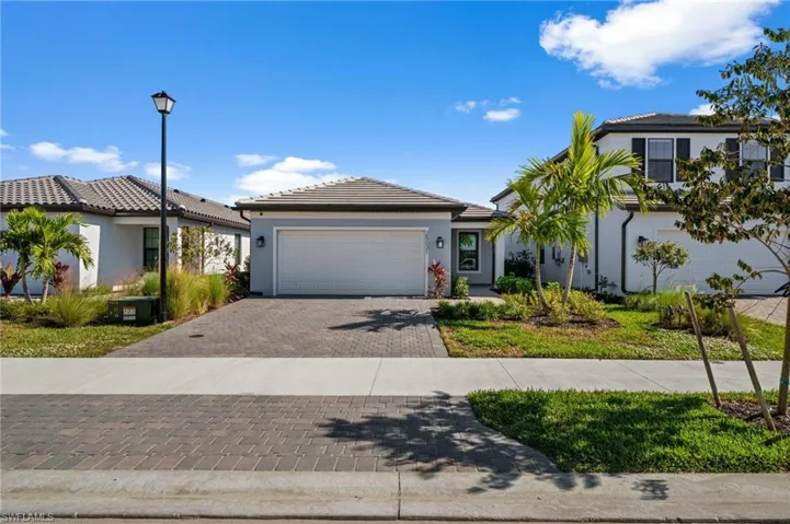 Single story home with stucco siding, decorative driveway, an attached garage, and a tile roof