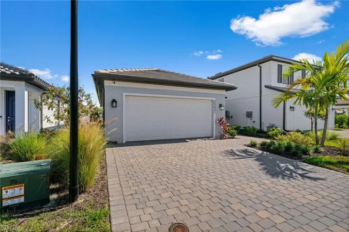 View of front of property featuring decorative driveway, a garage, and stucco siding