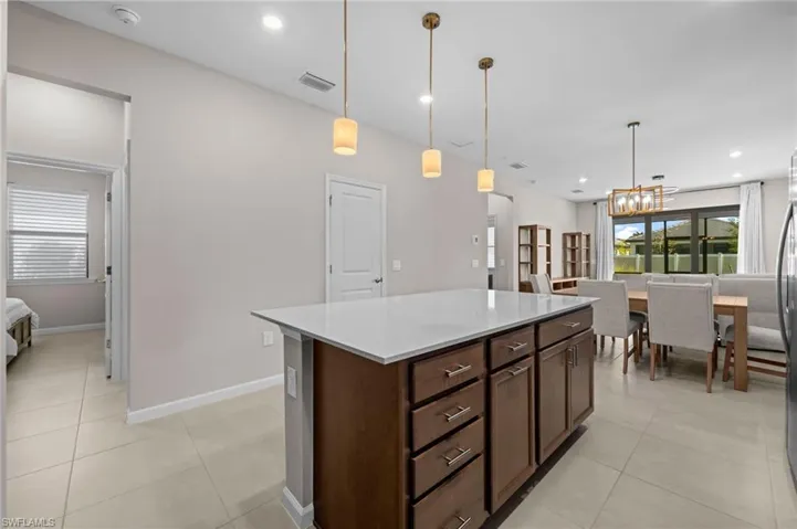 Kitchen with pendant lighting, a center island, recessed lighting, light tile patterned flooring, and light stone counters
