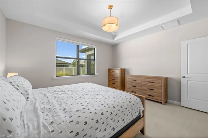 Bedroom featuring a raised ceiling, attic access, and tile patterned floors