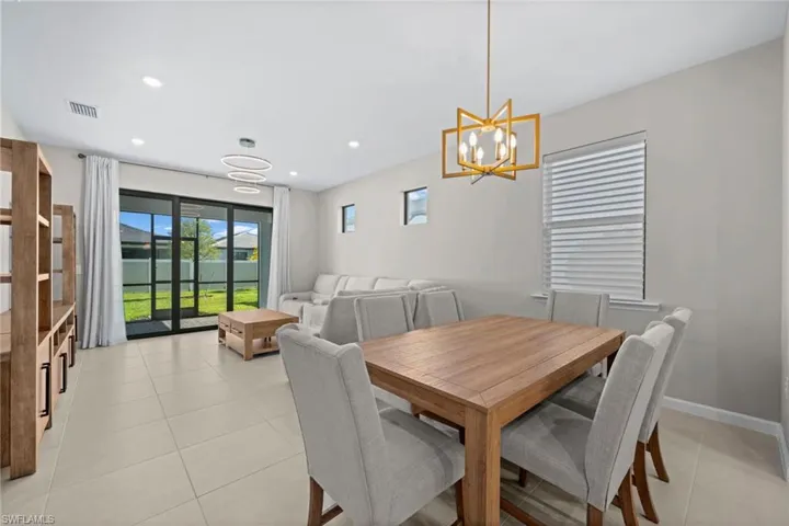 Dining area featuring light tile patterned floors, a water view, recessed lighting, and a chandelier