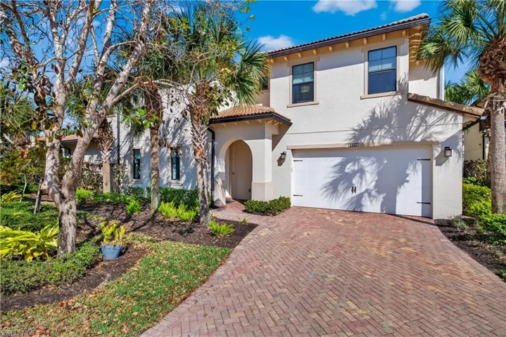 Front of home with a 2 car attached garage, paver driveway, stucco siding, and a tile roof