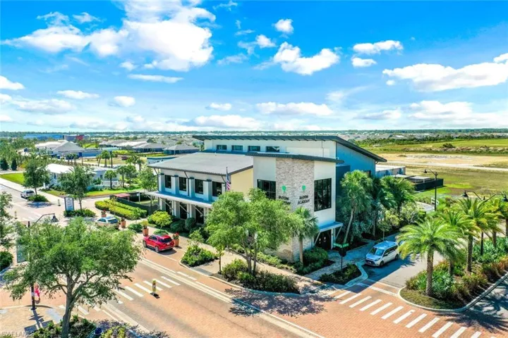 Modern commercial building featuring a stone facade and sloped roofline, surrounded by lush landscaping with palm trees and mature oaks