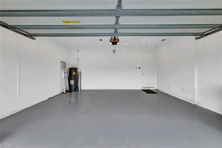 Spacious garage featuring a durable gray epoxy floor coating, recessed lighting, and a crisp white interior finish