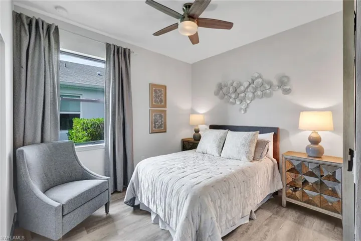 Room featuring wood-finish flooring, a ceiling fan with integrated lighting, and a window with grey drapery