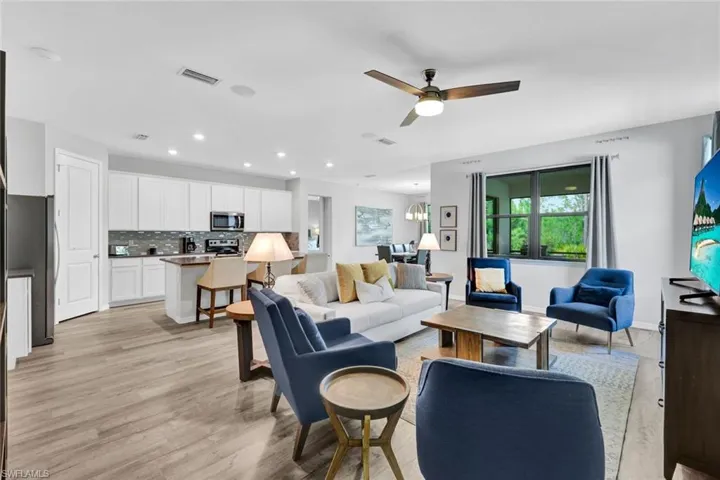 Open-concept living area with wood-finish flooring, recessed lighting, and a ceiling fan
