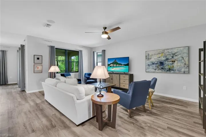 Spacious living area featuring wood-finish flooring, a ceiling fan with integrated lighting, and recessed lighting
