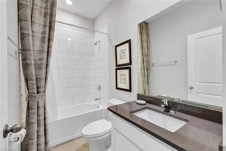 Bathroom featuring a single vanity with an integrated sink, dark countertop, and chrome faucet