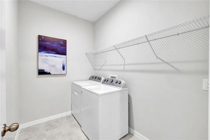 Dedicated laundry space featuring a top-load washer and dryer, practical wire shelving, light gray wall paint, and neutral tile flooring