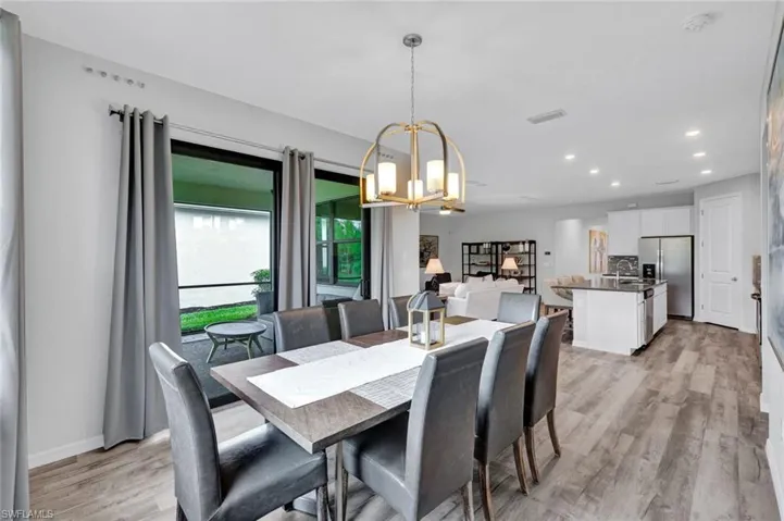 Open-concept dining area featuring wood-finish flooring, a contemporary chandelier, recessed lighting, and sliding glass doors to the outdoor living space