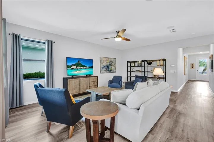 Spacious living area featuring light wood-finish flooring, a ceiling fan with integrated lighting, and recessed lighting