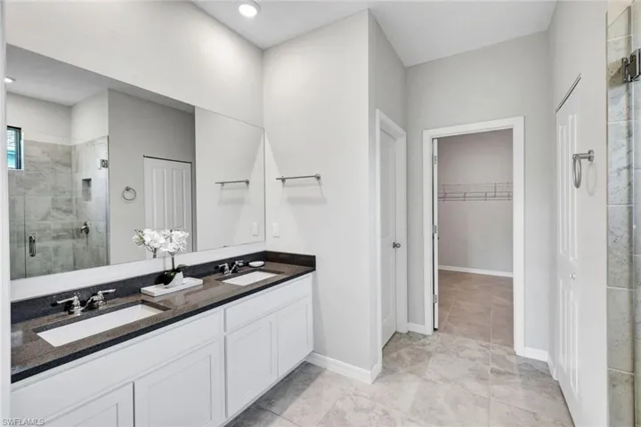 Bathroom featuring a double vanity with white cabinetry, dark countertops, and undermount sinks