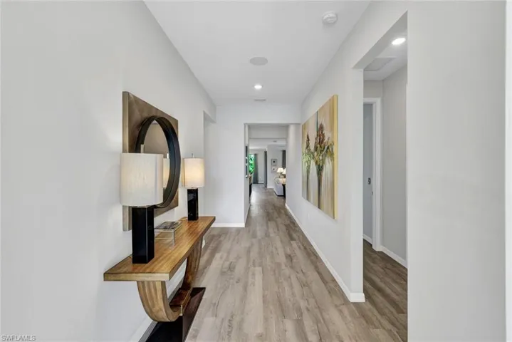 Spacious hallway featuring wood-finish flooring, recessed lighting, and crisp white walls